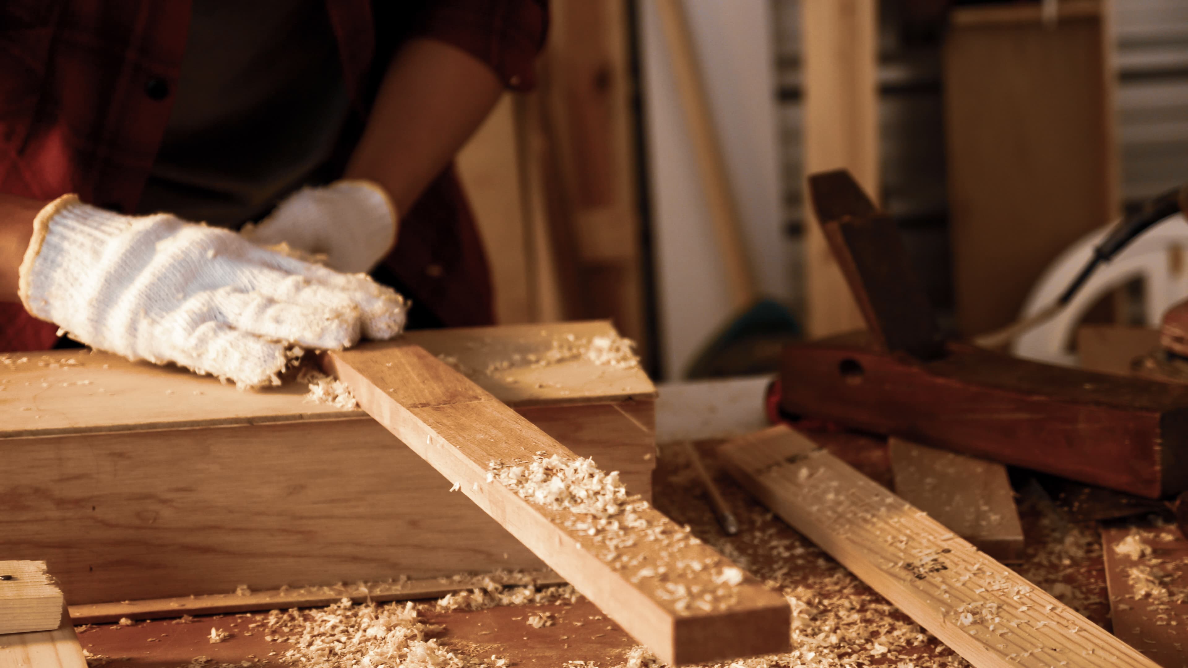 Manos dando forma manual a una pieza de madera.