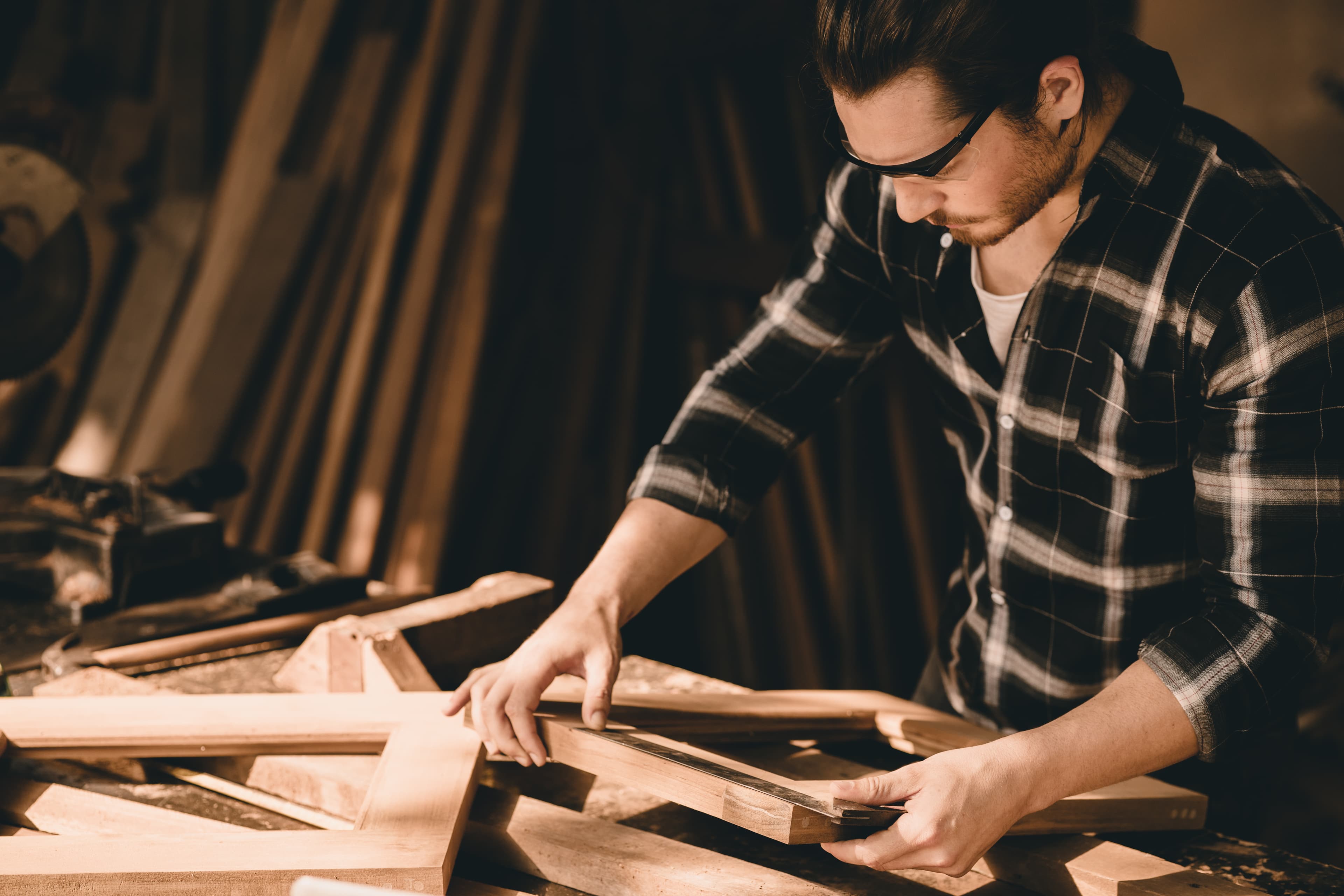 Persona revisando piezas de madera en el taller.